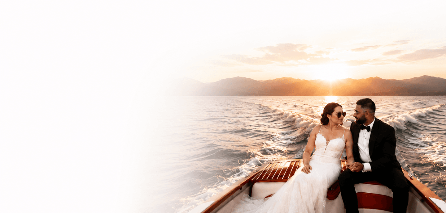Couple in traditional wedding attire watching the sunset over water